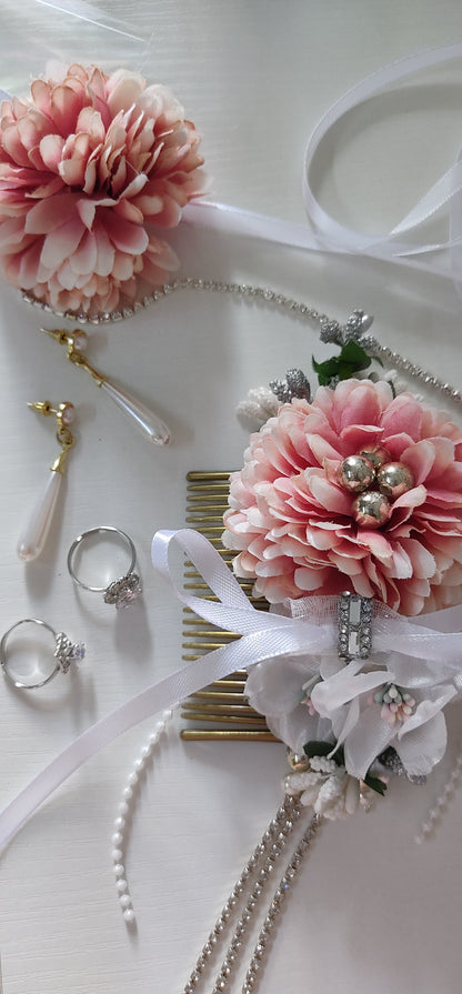Decorative hair accessories with pink flowers and jewelry on a white surface