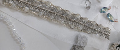 Silver beaded belt with jewelry on a white surface