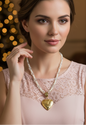 Woman wearing a pearl necklace with a heart pendant in a warm, blurred indoor setting