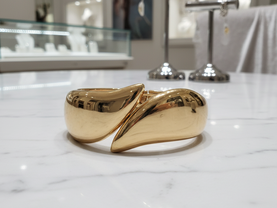 Gold bracelet on a marble surface with a blurred background