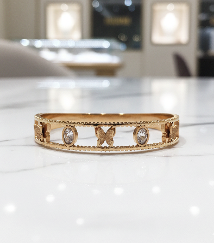 Gold bracelet with butterfly and diamond designs on a white surface