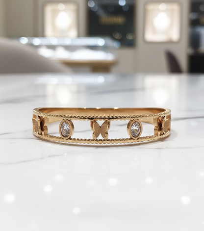 Gold bracelet with butterfly and diamond designs on a white surface