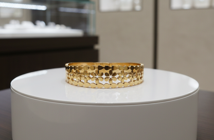 Gold bracelet on a white stand with a jewelry display in the background
