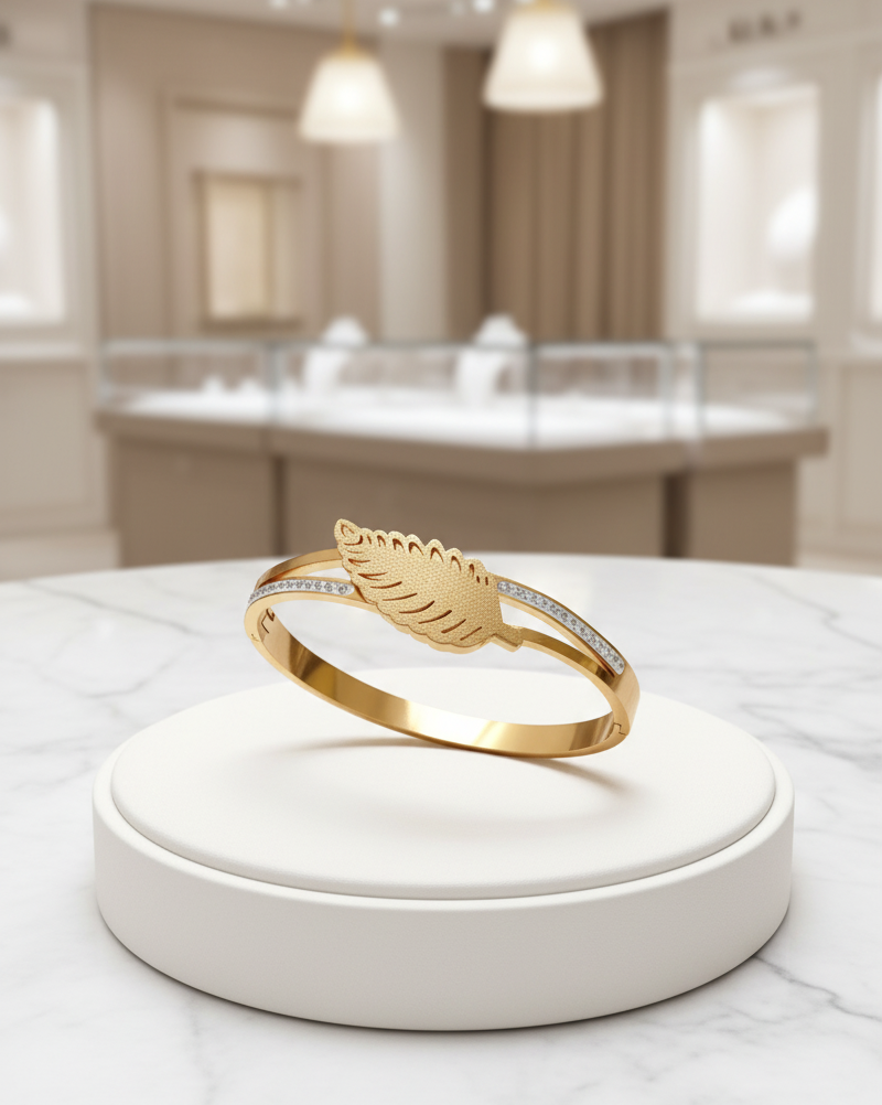 Gold ring with feather design on a white stand in a store setting