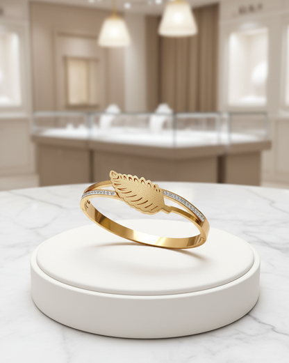 Gold ring with feather design on a white stand in a store setting