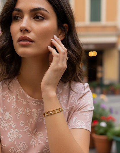 Woman wearing gold bracelets and a ring in an outdoor setting