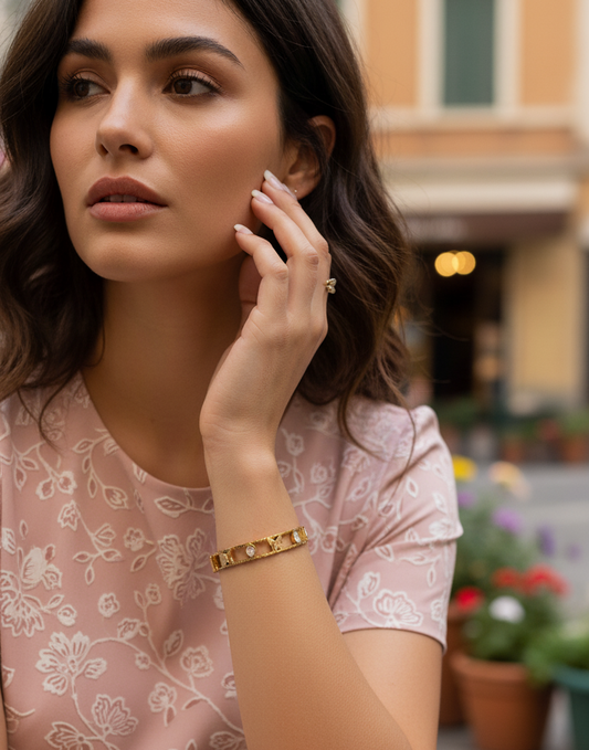 Woman wearing gold bracelets and a ring in an outdoor setting