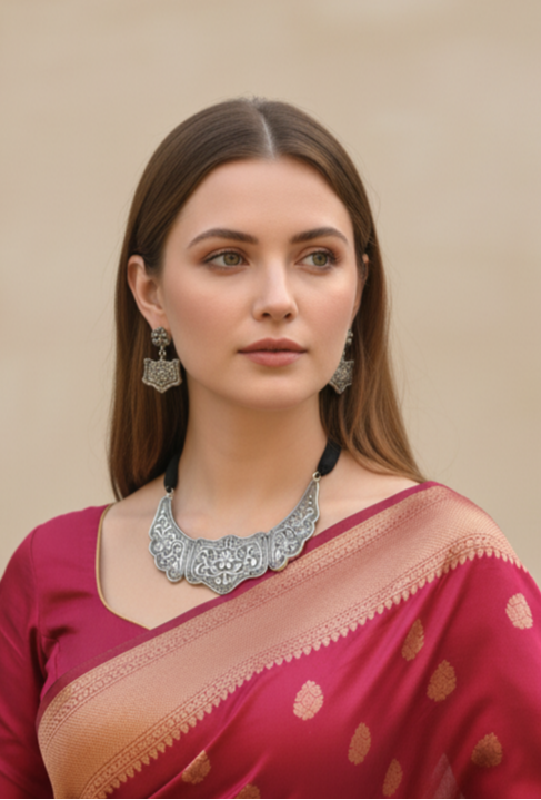 Woman wearing a red saree with gold patterns against a beige background
