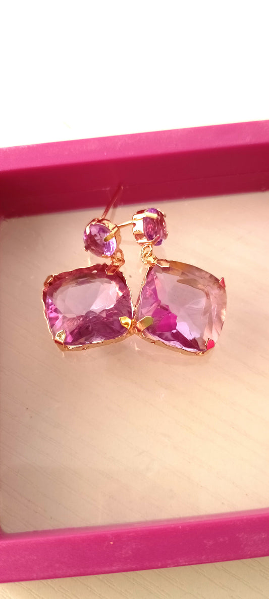 Pink gemstone earrings on a pink background