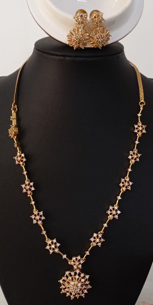 Gold necklace and earrings on a black mannequin with a white background