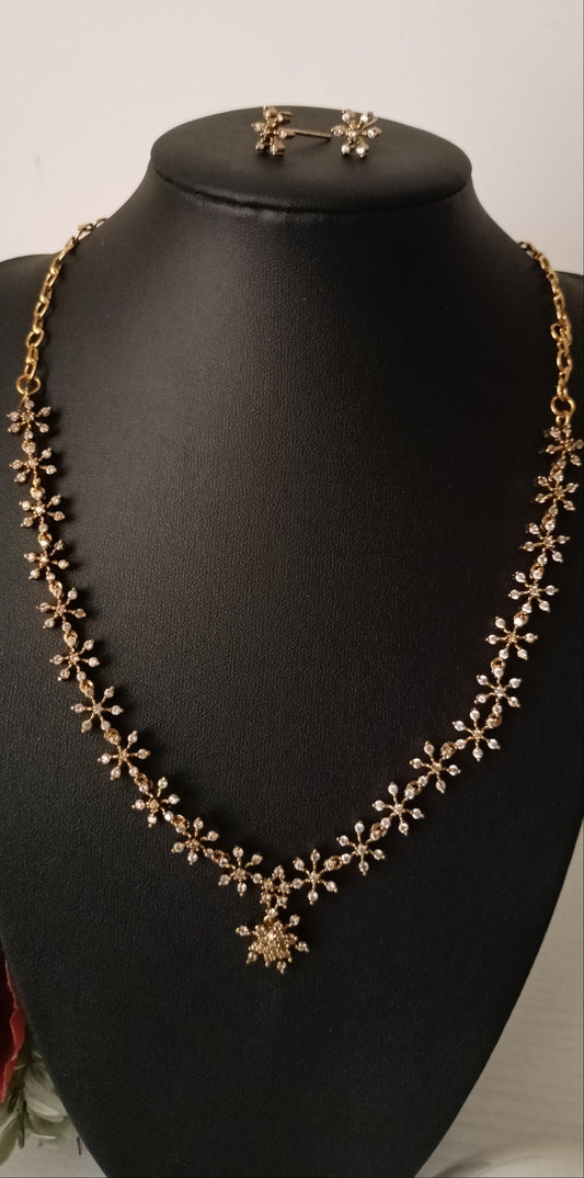 Gold necklace and earrings on a black mannequin bust against a white background