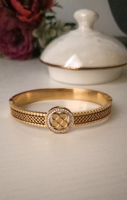 Gold bracelet with intricate design on a light background