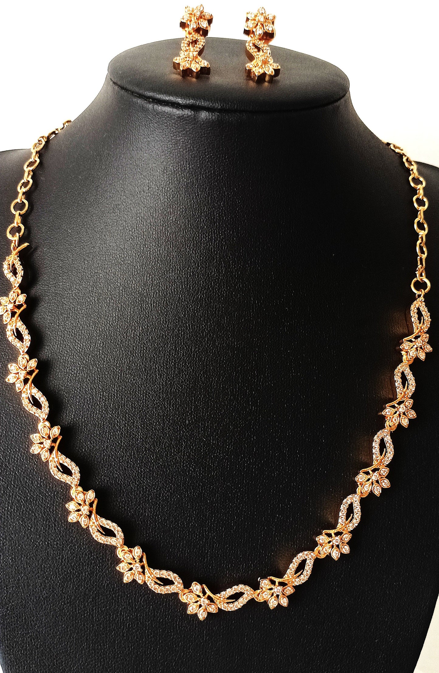 Gold necklace and earrings on a black mannequin bust