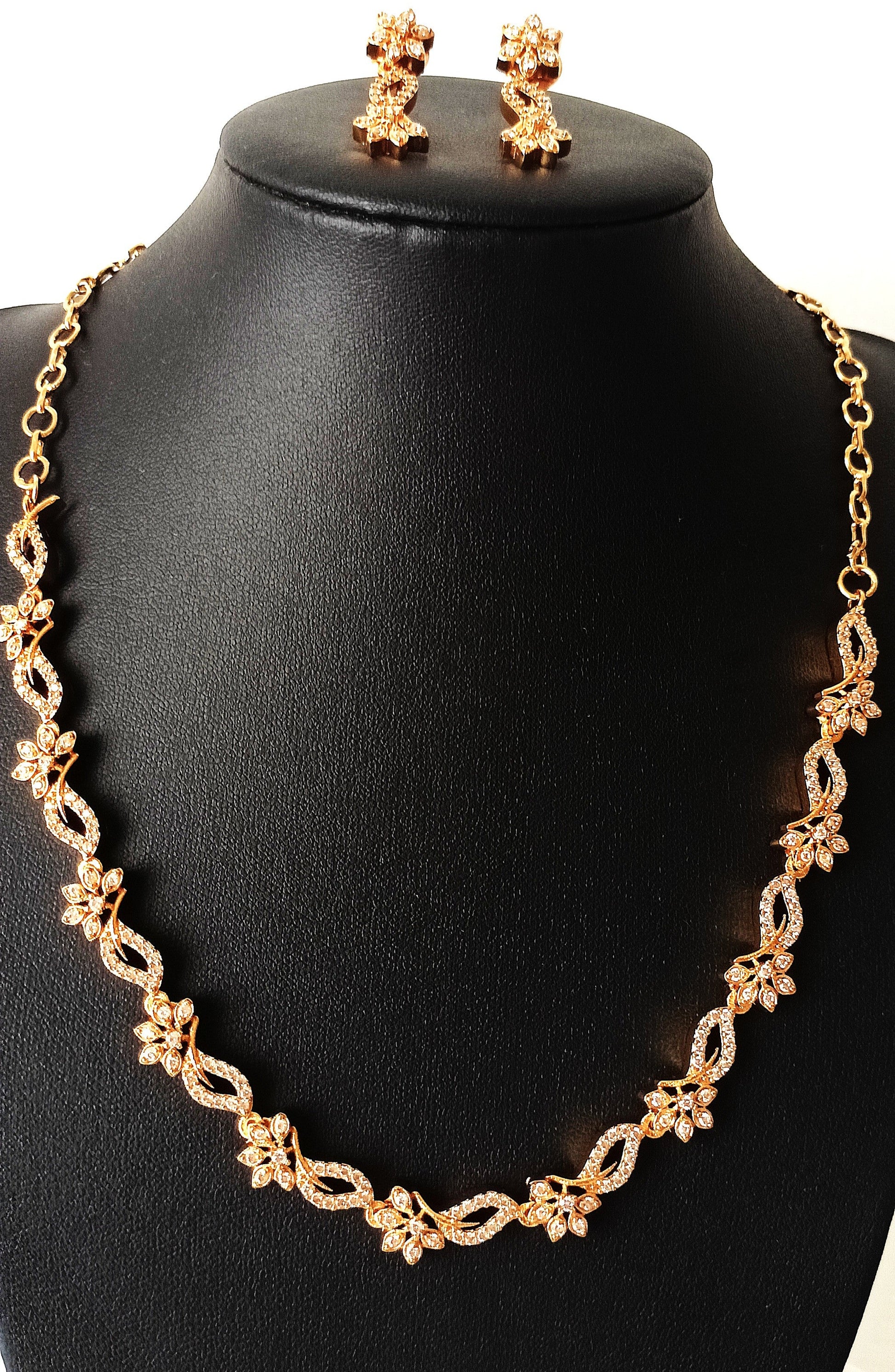 Gold necklace and earrings on a black mannequin bust