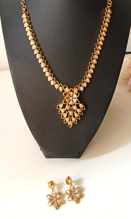 Gold necklace and earrings on a black mannequin bust.
