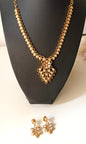 Gold necklace and earrings on a black mannequin bust.