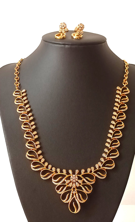 Gold necklace and earrings on a black mannequin with a floral background