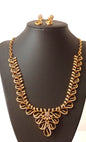 Gold necklace and earrings on a black mannequin with a floral background