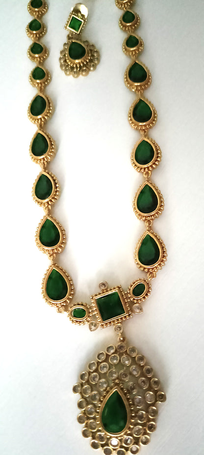 Gold necklace with green gemstones on a white background