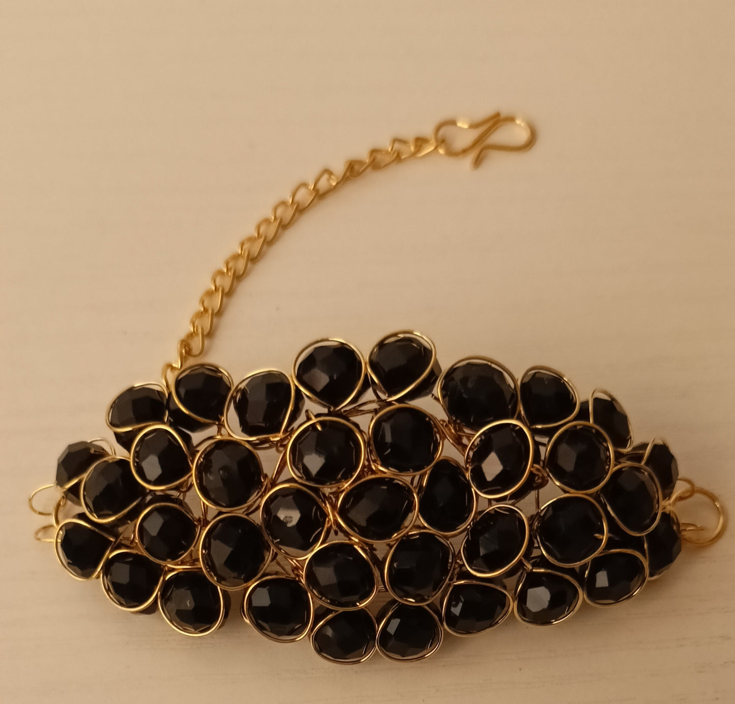 Bracelet with black beads and gold chain on a beige background