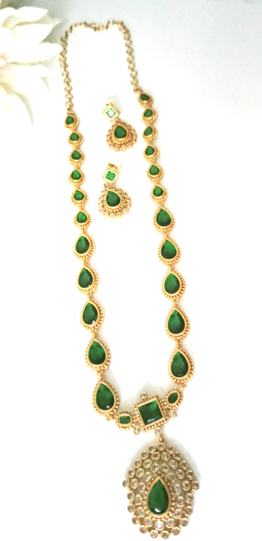 Gold necklace with green gemstones on a white background