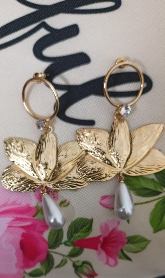 Gold leaf earrings with silver accents on a floral background