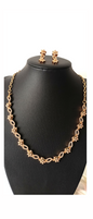 Gold necklace and earrings on a black mannequin bust against a white background