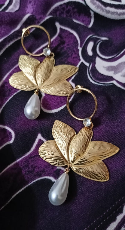 Gold leaf earrings with pearl drops on a purple fabric background